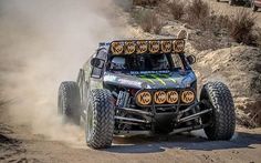 a truck driving down a dirt road with dust coming off the front wheels and tires