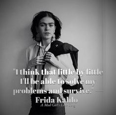 a woman standing in front of a white wall with a quote from frida kallo