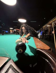 a woman leaning over a pool table with a ball in front of her on the edge