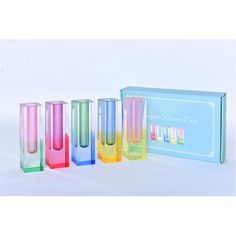 four different colored vases sitting next to each other in front of a blue box