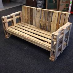 a wooden bench made out of pallets on the floor in front of some boxes