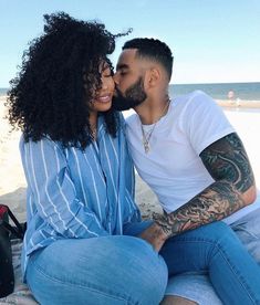 a man and woman sitting next to each other on the beach