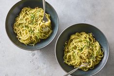 two bowls filled with pasta and topped with parsley on the side, next to each other