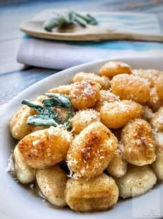 a white plate topped with fried bananas covered in powdered sugar and sprinkled with sage