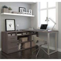 a desk with a laptop computer on top of it next to a chair and window