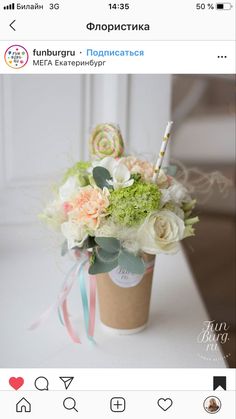 a cup filled with flowers sitting on top of a table next to an iphone screen