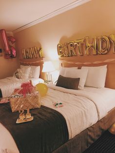 a bed room with two beds and balloons on the headboard, in front of a wall that says happy birthday