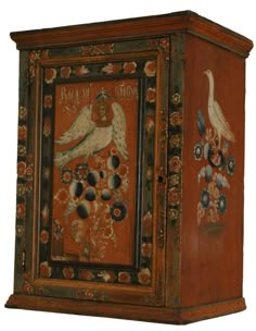 an ornate wooden box with two birds painted on the front and sides, sitting against a white wall