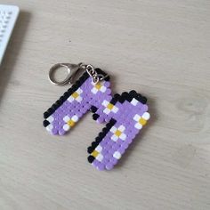 a pair of pixel keychains sitting on top of a wooden table next to a computer keyboard