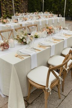 a long table set up with white linens and flowers