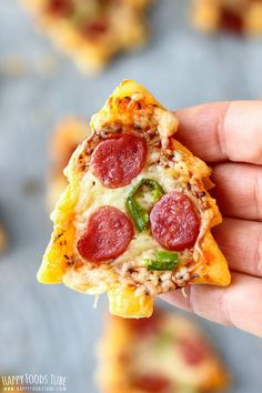 a slice of pizza with pepperoni, green peppers and cheese is held up to the camera