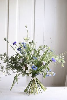 a vase filled with blue and white flowers sitting on top of a table next to a wall