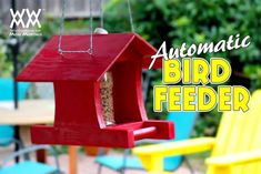 a red bird feeder hanging from the side of a table