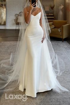 a woman in a wedding dress taking a selfie with her cell phone while wearing a veil