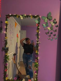 a woman taking a selfie in front of a mirror with butterflies on the wall