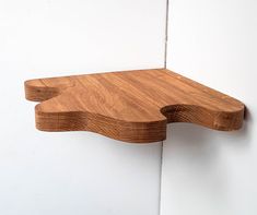 a wooden shelf mounted to the side of a white wall with a wood design on it