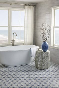 a bath tub sitting next to a window in a room with blue and white decor