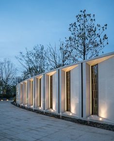 a row of white walls with lights on each side and trees in the back ground