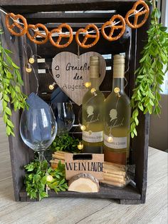 two bottles of wine and some pretzels on a wooden crate with greenery