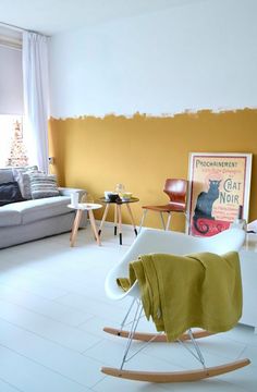 a living room with yellow walls and white tile flooring, including a rocking chair