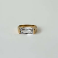 a gold ring with a baguette cut diamond in the center on a white background