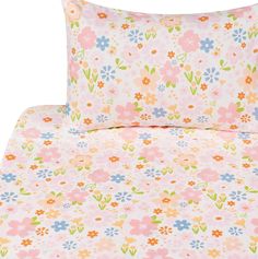 a bed with pink and blue flowers on the sheets, pillows and pillowcases