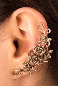 a close up of a person's ear with flowers and leaves attached to it