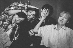 black and white photograph of four boys posing for the camera with their arms around each other