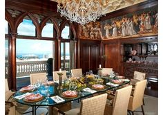 a dining room table set with plates and glasses in front of a large window overlooking the ocean