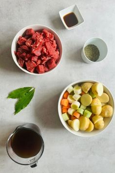 two bowls filled with meat and vegetables next to a cup of tea