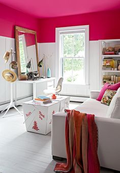 a living room with pink walls and white furniture