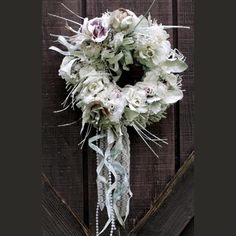 a wreath with white flowers hanging on a wooden door