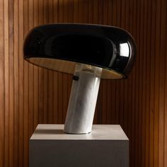 a black and white lamp sitting on top of a table next to a wooden wall