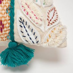 an embroidered pillow with tassels on it