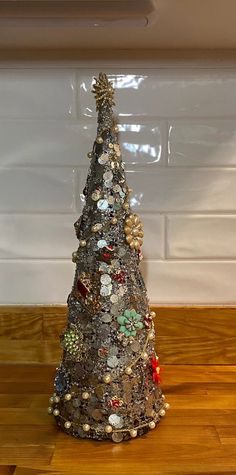 a small christmas tree made out of old buttons and other items on a wooden table