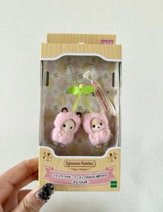 two small stuffed animals in a box with keychain attached to it's ear