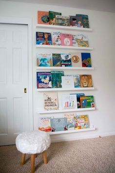 a white book shelf filled with lots of books next to a wall mounted on the side of a door