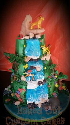 a three tiered cake decorated with animals and trees on it's sides, in the shape of a waterfall