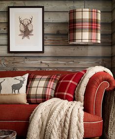 a living room filled with furniture next to a wall covered in wood planks and plaid pillows