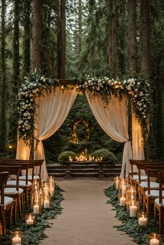 an outdoor wedding setup with candles and greenery on the aisle, surrounded by tall trees