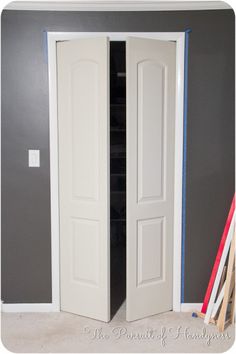 an open closet door in a room with gray walls and white trim on the doors