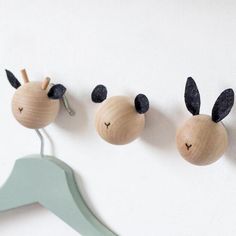 three wooden bugs hanging on the wall with clothes pins attached to them, and one has ears sticking out