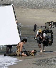 a man laying on the beach next to a woman in front of a white board