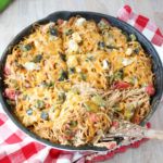 a skillet filled with pasta and vegetables on top of a checkered table cloth