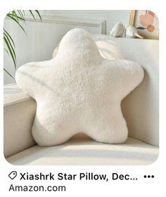 a white star pillow sitting on top of a couch next to a potted plant