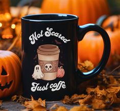 a black coffee mug sitting on top of a table next to pumpkins and jack - o'- lanterns