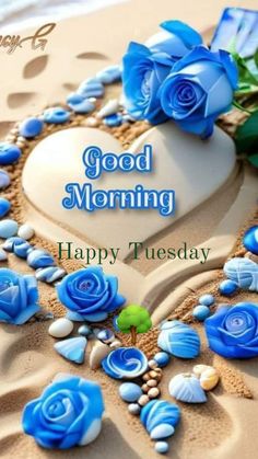 a heart shaped cake with blue roses and seashells on the sand, says good morning happy tuesday