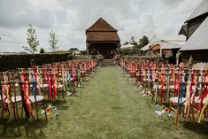 rows of chairs lined up in front of a barn with balloons on the grass and ribbons tied to them