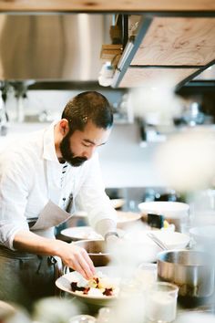 a man in a kitchen preparing food on top of a white plate with utensils