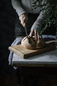 a person cutting bread on top of a wooden table